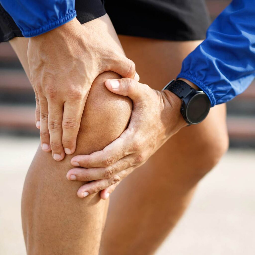 Close-up of hands holding a knee, representing runner's knee pain and discomfort during running.