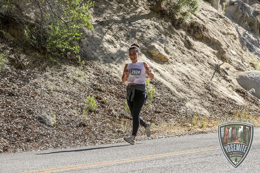 A female runner happily running downhill on a road during a race.