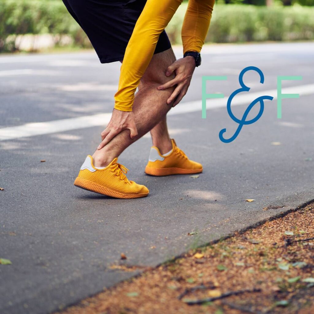 Achilles pain in runners – a runner crouches down, gripping their right Achilles in discomfort.