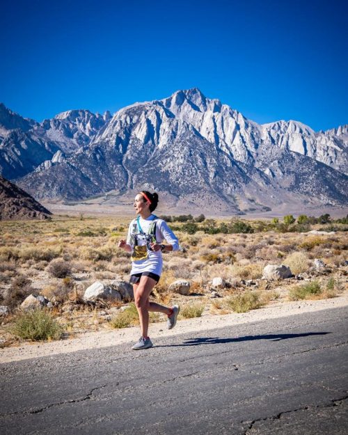 A runner on a scenic road with a mountain range in the background.